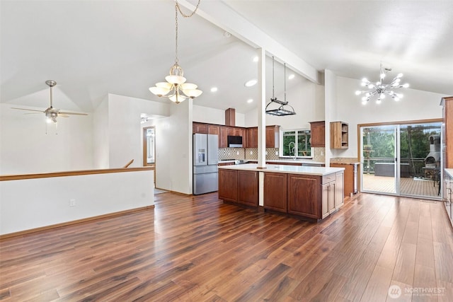 kitchen featuring a kitchen island, backsplash, appliances with stainless steel finishes, light countertops, and high vaulted ceiling