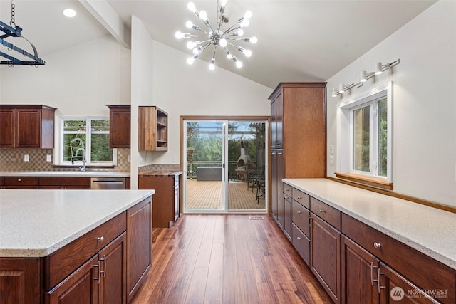 kitchen with plenty of natural light, decorative backsplash, wood finished floors, and a notable chandelier