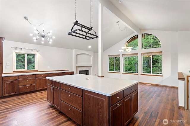 kitchen featuring an inviting chandelier, light countertops, a wealth of natural light, vaulted ceiling with beams, and a tile fireplace