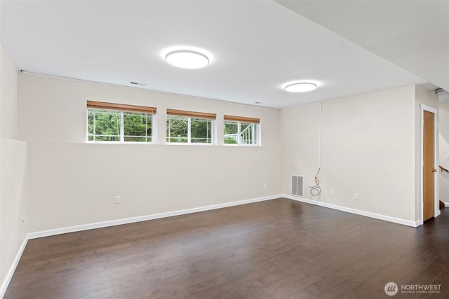 spare room featuring visible vents, baseboards, a healthy amount of sunlight, and dark wood-style floors