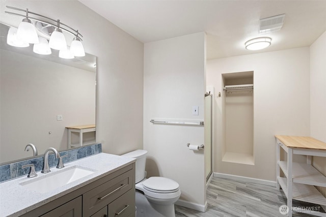 bathroom with vanity, toilet, baseboards, wood finished floors, and visible vents