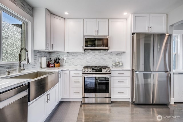 3012 N 30th St, Tacoma, WA 98407 - kitchen featuring white cabinets, tasteful backsplash, light stone counters, a sink, and appliances with stainless steel finishes