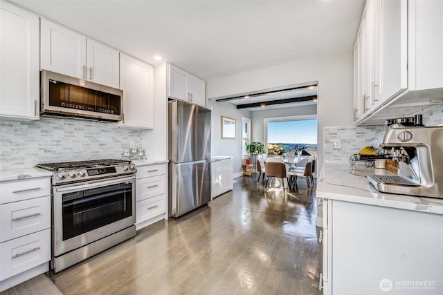 3012 N 30th St, Tacoma, WA 98407 - kitchen with decorative backsplash, wood finished floors, light stone countertops, white cabinets, and stainless steel appliances