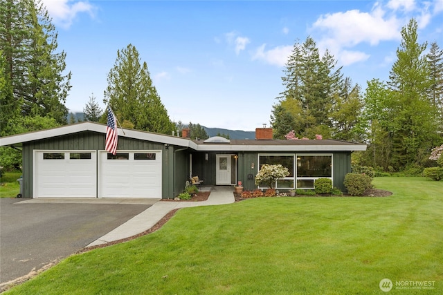 13203 436th Ave SE, North Bend, WA 98045 - view of front of house with a garage, a front lawn, a chimney, board and batten siding, and driveway