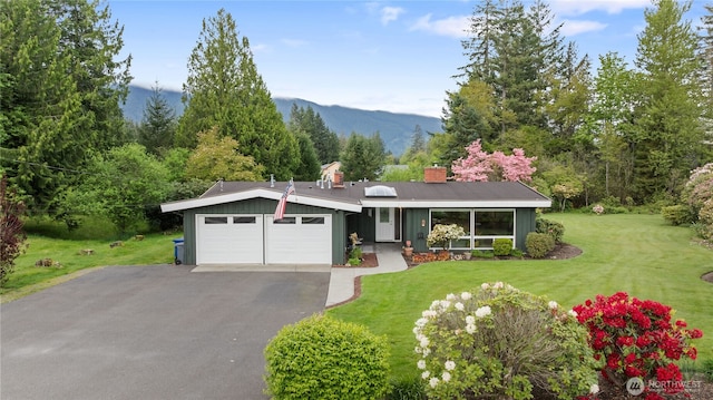 13203 436th Ave SE, North Bend, WA 98045 - view of front of home with driveway, a chimney, a mountain view, a front lawn, and an attached garage