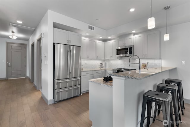 4961 Main St Unit 612, Tacoma, WA 98407 - kitchen featuring stainless steel appliances, a peninsula, a kitchen bar, baseboards, and recessed lighting