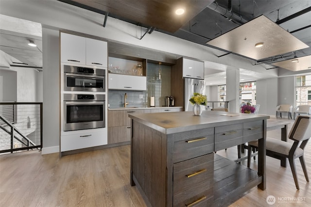 4961 Main St Unit 612, Tacoma, WA 98407 - kitchen featuring modern cabinets, stainless steel appliances, white cabinetry, and light wood-style floors