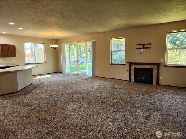 unfurnished living room with an inviting chandelier, a wealth of natural light, and a tile fireplace
