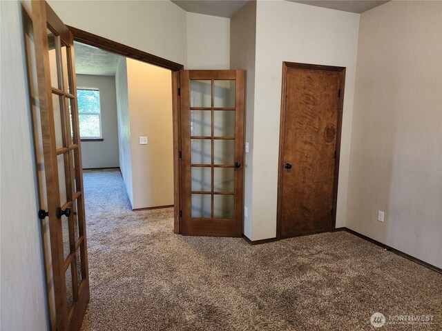 carpeted empty room with baseboards and french doors