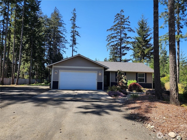 ranch-style home with an attached garage, fence, and aphalt driveway