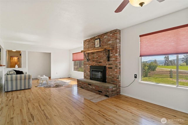 177 Salmon Creek Rd, Okanogan, WA 98840 - unfurnished living room featuring plenty of natural light, ceiling fan, a fireplace, and light wood-type flooring