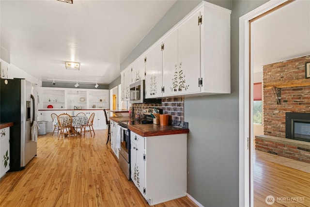 177 Salmon Creek Rd, Okanogan, WA 98840 - kitchen featuring light wood-style flooring, white cabinets, a fireplace, and stainless steel appliances