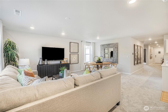 living area featuring recessed lighting, baseboards, visible vents, and light carpet