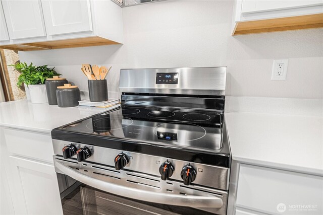 interior details featuring light countertops, electric range, and white cabinetry