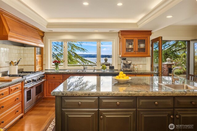 kitchen featuring a water view, custom exhaust hood, double oven range, and a sink