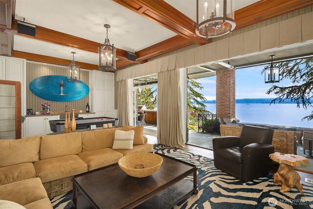 living area featuring a water view, beamed ceiling, and an inviting chandelier