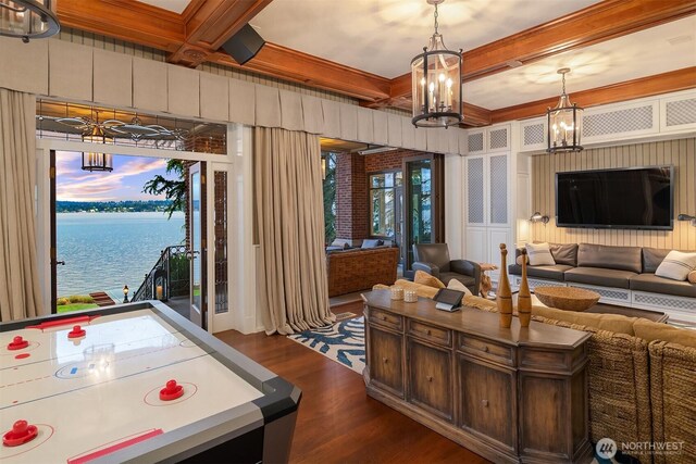 rec room featuring an inviting chandelier, dark wood-style flooring, a water view, and coffered ceiling