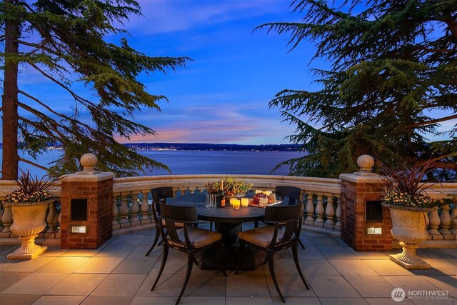 patio terrace at dusk featuring a water view and outdoor dining space