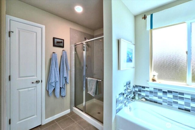 bathroom with a bath, baseboards, tile patterned flooring, and a stall shower