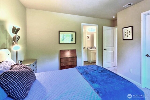 carpeted bedroom featuring visible vents, baseboards, and ensuite bathroom