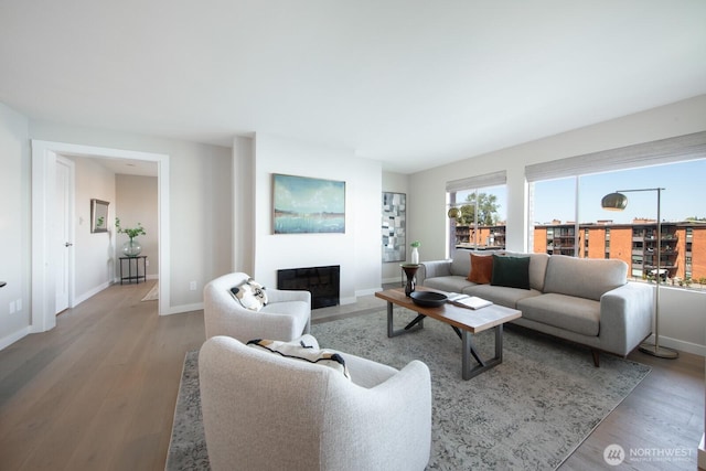 living area with baseboards, a fireplace with flush hearth, and wood finished floors