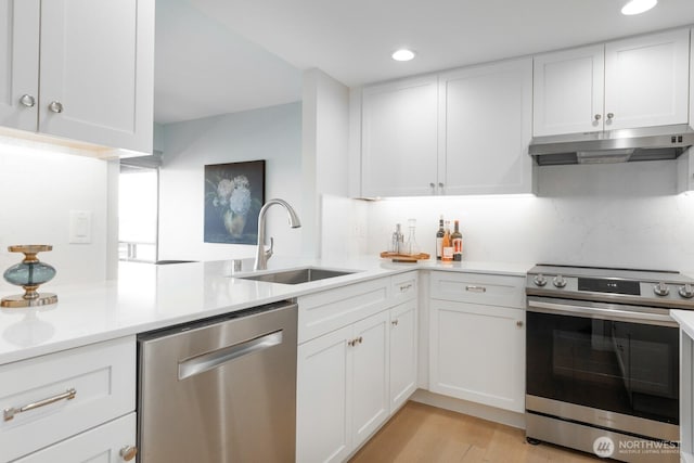 kitchen featuring light countertops, under cabinet range hood, white cabinets, a sink, and appliances with stainless steel finishes