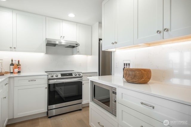 kitchen featuring white cabinets, light wood finished floors, light countertops, stainless steel appliances, and under cabinet range hood