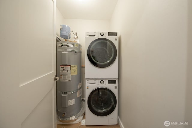 laundry room with baseboards, strapped water heater, stacked washer / drying machine, and laundry area