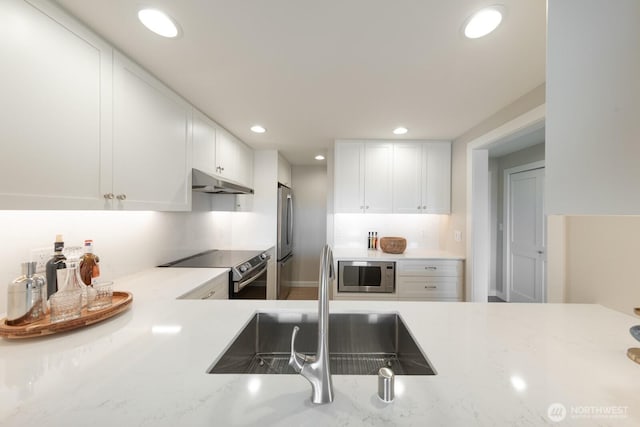 kitchen with a sink, stainless steel appliances, recessed lighting, white cabinetry, and under cabinet range hood