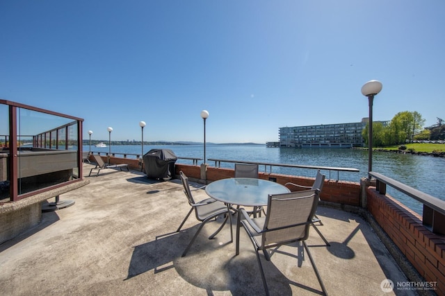 view of patio with area for grilling and a water view