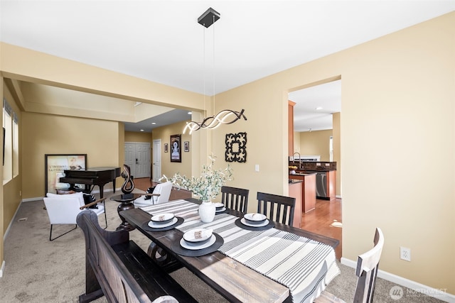 dining room featuring baseboards and light colored carpet
