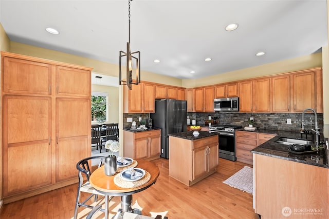 kitchen featuring a sink, appliances with stainless steel finishes, backsplash, and a kitchen island