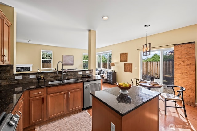 kitchen featuring stainless steel dishwasher, decorative backsplash, dark stone countertops, a sink, and light wood finished floors