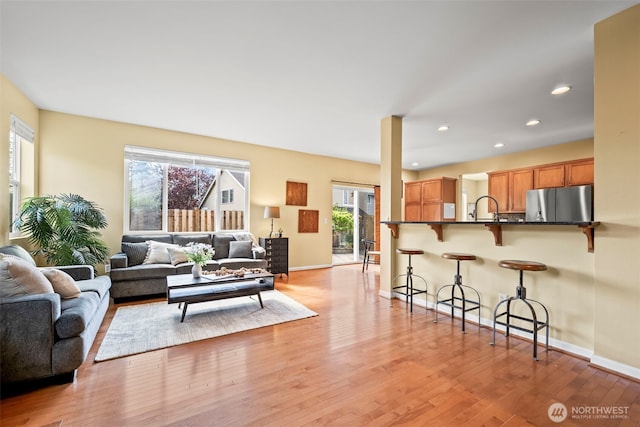 living room with recessed lighting, baseboards, plenty of natural light, and light wood finished floors