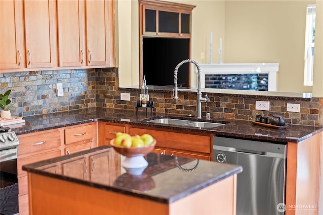 kitchen featuring appliances with stainless steel finishes, a sink, dark stone countertops, backsplash, and a kitchen island