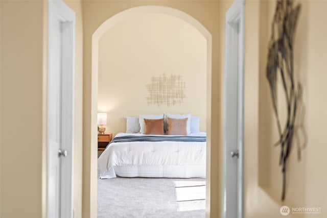 carpeted bedroom with arched walkways