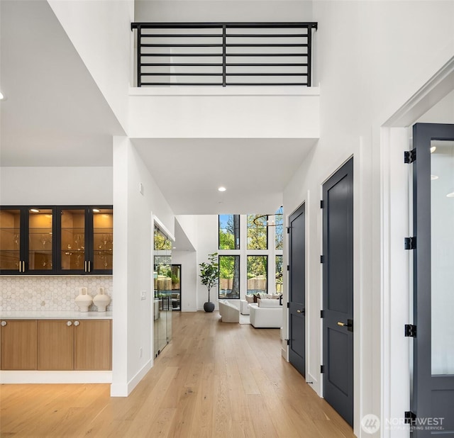 foyer featuring recessed lighting, baseboards, light wood finished floors, and a towering ceiling