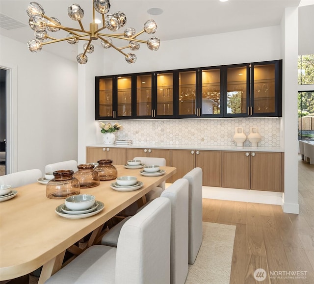 dining area featuring an inviting chandelier, visible vents, and light wood-style floors