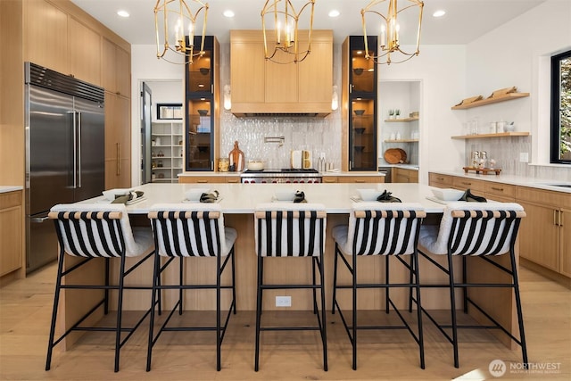 kitchen with an inviting chandelier, built in refrigerator, tasteful backsplash, and a large island