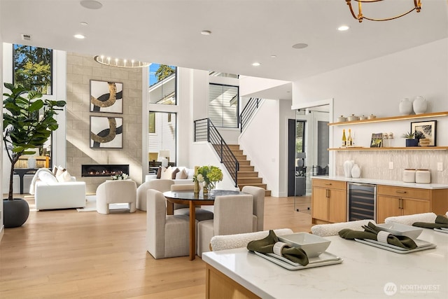 dining area with light wood-style floors, stairs, wine cooler, bar area, and recessed lighting