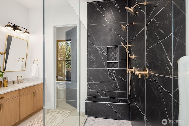bathroom featuring toilet, a marble finish shower, and vanity