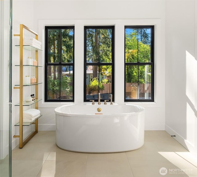 bathroom with baseboards, tile patterned floors, and a soaking tub