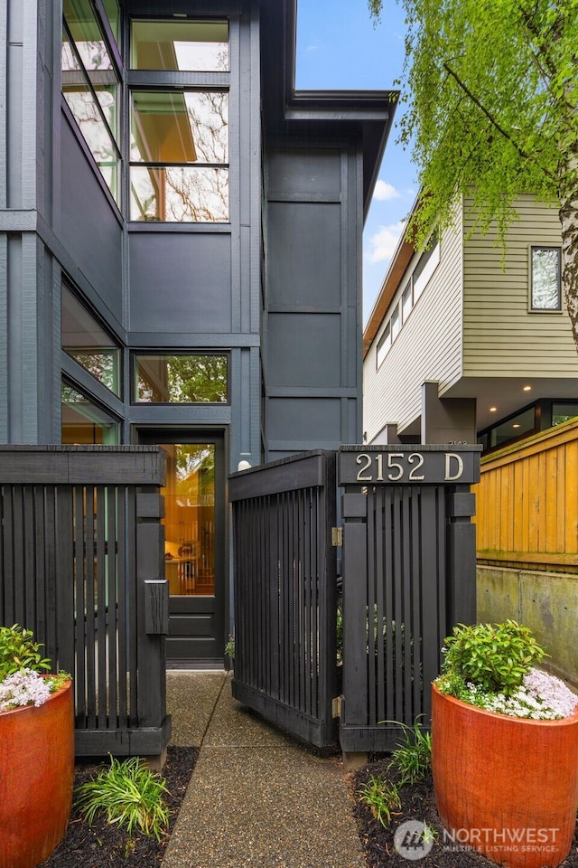 rear view of property featuring fence and a gate