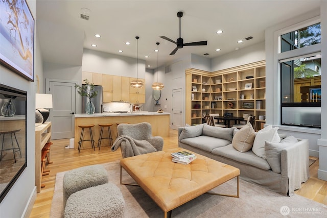 living area with a ceiling fan, recessed lighting, visible vents, and light wood-style floors