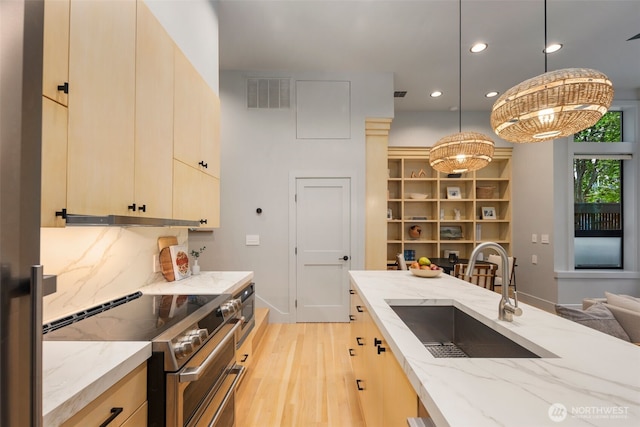 kitchen with a sink, light wood-style floors, range with two ovens, recessed lighting, and visible vents