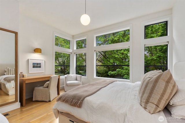 bedroom with visible vents, multiple windows, and light wood-style floors