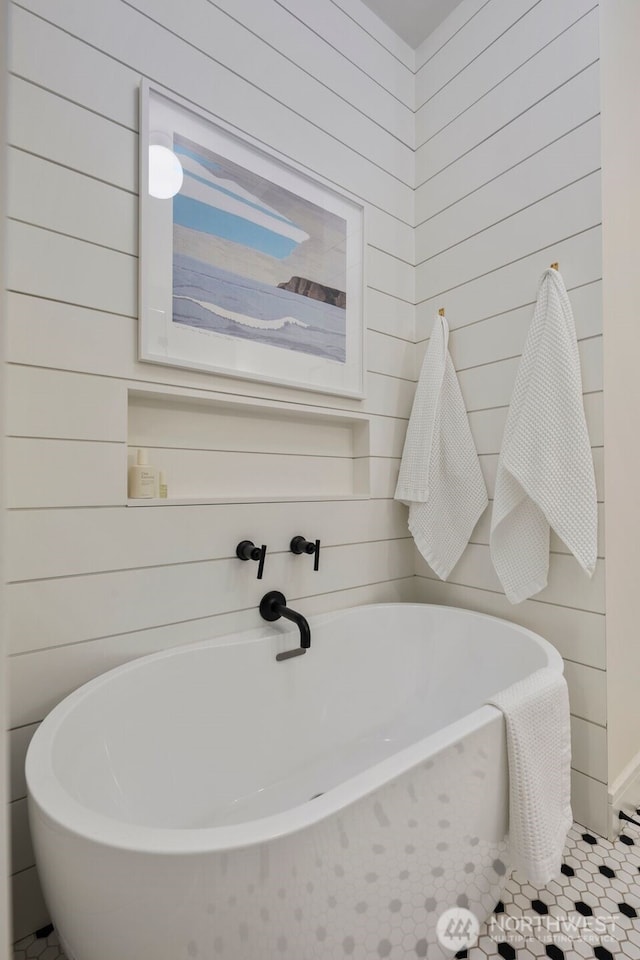 bathroom with wood walls and a soaking tub