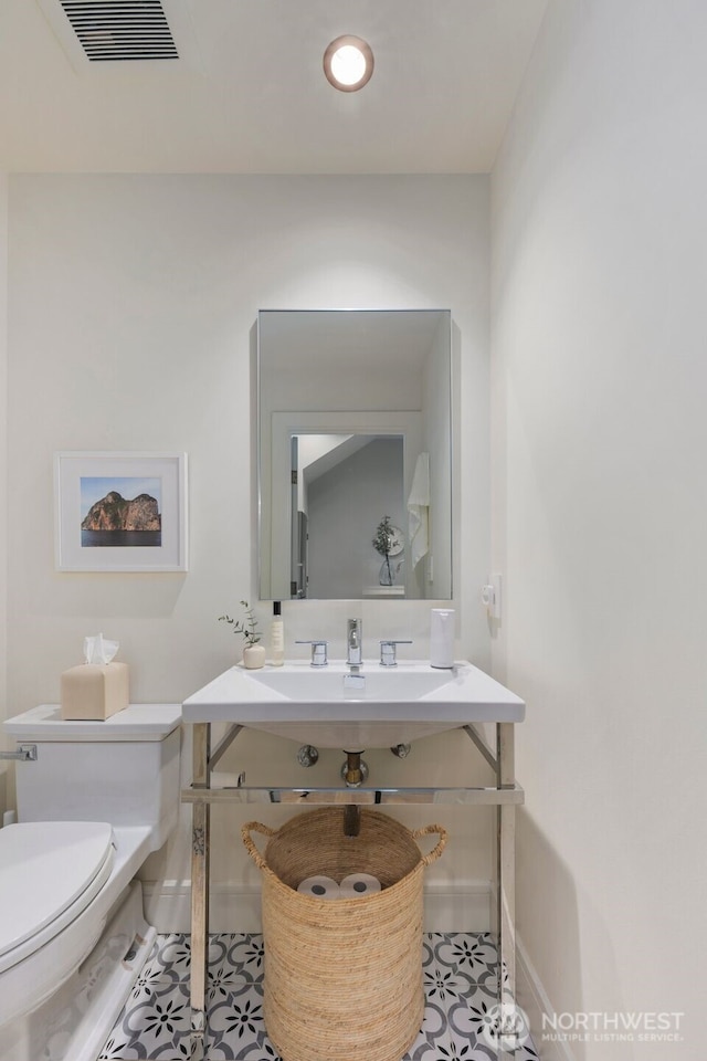 half bath featuring baseboards, tile patterned flooring, toilet, and visible vents