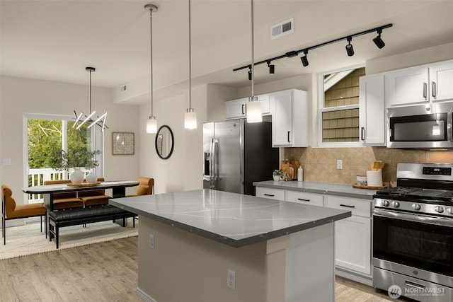 kitchen with a kitchen island, visible vents, rail lighting, light wood-style floors, and stainless steel appliances