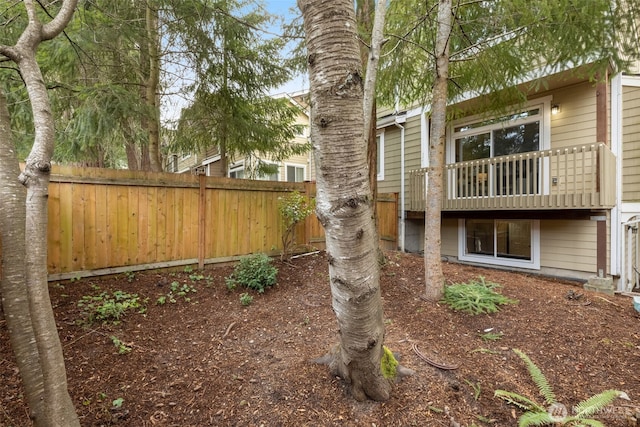 view of yard featuring fence and a balcony